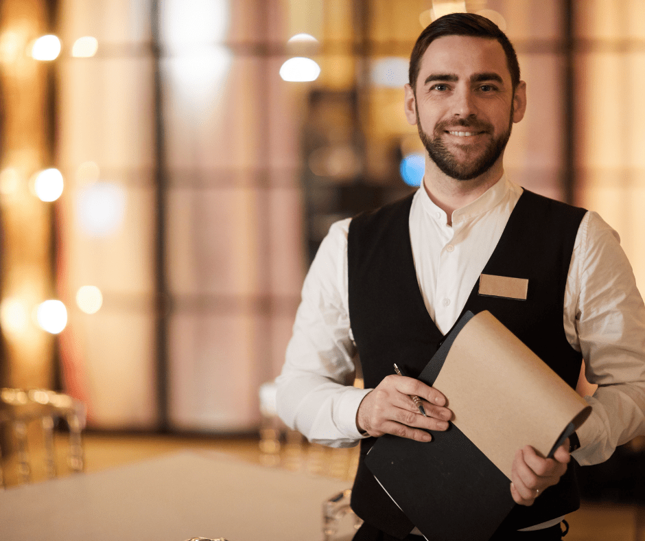 Maître recebendo clientes na entrada do salão de um restaurante